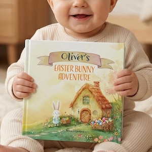 May include: A smiling baby holds a book titled "Oliver's Easter Bunny Adventure." The book cover features a whimsical illustration of a bunny, a cottage, and a cart of Easter eggs. The background is a soft, neutral color.