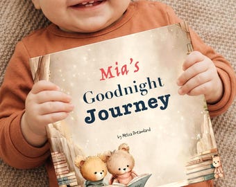 May include: A smiling baby holds a children's book titled "Mia's Goodnight Journey." The book cover features illustrations of two teddy bears reading, with stacks of books on either side. The baby is wearing a rust-colored onesie.