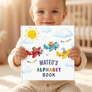 May include: A square hardcover book with a white cover featuring a yellow sun, blue clouds, and three colorful airplanes piloted by a bear, a fox, and a rabbit. The text reads MATEO'S ALPHABET BOOK in blue and multicolored letters.