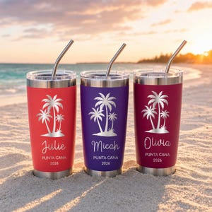 Puede incluir: Tres vasos de acero inoxidable con tapas transparentes y pajitas de metal. Los vasos rojo, morado y granate presentan un gráfico de palmera blanca, los nombres Julie, Micah u Olivia y el texto PUNTA CANA 2026 grabado en la parte frontal.