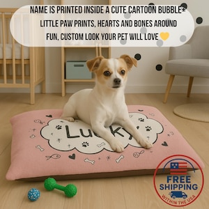 May include: A dog bed with the name "Lucky" printed on it, surrounded by paw prints, hearts, and bones. The bed is pink with a brown border. A small dog is lying on the bed. The text on the image says "Name is printed inside a cute cartoon bubble, little paw prints, hearts and bones around, fun, custom look your pet will love."
