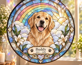 May include: A circular stained glass suncatcher featuring a golden retriever portrait centered against a rainbow and sun background. White lilies frame the dog. A central plaque displays the text Buddy 2012-2026 with two paw prints and a heart.