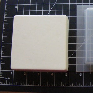 May include: Two square silicone moulds, one white and one clear, on a black grid background. The white mould is 4 inches wide and the clear mould is 7 inches wide.