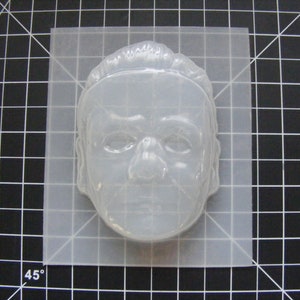 May include: A clear plastic mold of a human face, suitable for making crafts or soap.