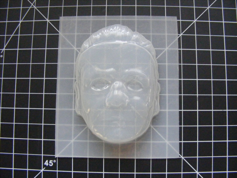 May include: A clear plastic mold of a human face, suitable for making crafts or soap.