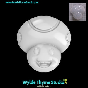 May include: White plastic mold of a mushroom with a smiling face. The mold is designed for making edible treats like chocolate or candy.