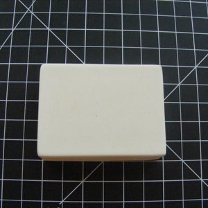 Puede incluir: Una baldosa cerámica rectangular blanca con una superficie lisa.