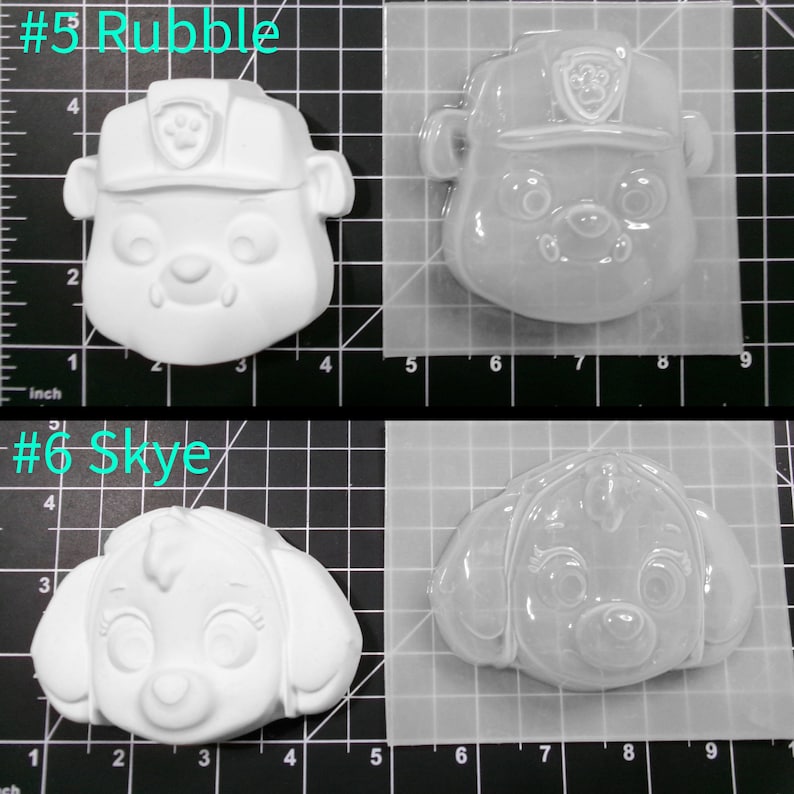 May include: Two clear plastic molds for making character-shaped crafts. The molds are shaped like the heads of the characters Rubble and Skye from the cartoon show Paw Patrol. The molds are approximately 3 inches wide and 3 inches tall.