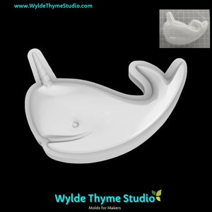 May include: White plastic mould of a narwhal with a horn. The mould is on a black background.