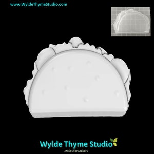 May include: White plastic mould of a taco shell. The mould is designed to create a realistic taco shell shape with a textured surface.