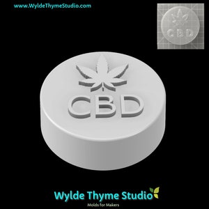 Puede incluir: Molde redondo blanco con un diseño en relieve de una hoja de cannabis y la palabra "CBD".