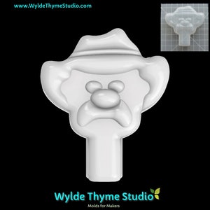 May include: White plastic mold of a cartoon face wearing a hat. The mold is designed for making soap, candles, or other crafts.