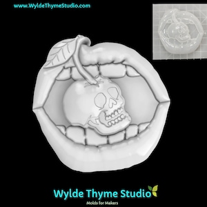 May include: A white silicone mold of a mouth with a skull inside an apple. The mold is on a black background.