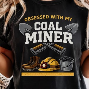 May include: A white ceramic mug with a black handle and the text "But First, Coffee" in a bold, black font. The mug is set against a blurred background, suggesting a cozy setting.