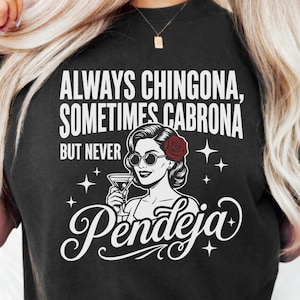 May include: Black t-shirt with the text "ALWAYS CHINGONA, SOMETIMES CABRONA BUT NEVER Pendeja" in white. The shirt features a graphic of a woman with sunglasses, a red rose, and a cocktail.