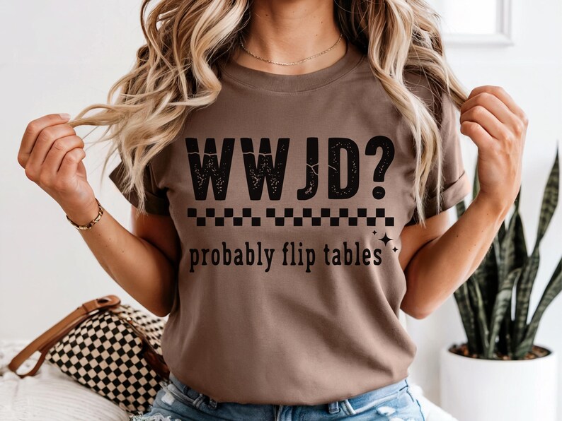 May include: A brown t-shirt with the text "WWJD? probably flip tables" in black. The shirt has a checkered pattern and star graphics. The shirt is a casual wear item.