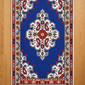 May include: A rectangular blue rug with an intricate pattern. The rug features a central diamond-shaped design in white, red, and blue, surrounded by paisley and floral motifs. The border is a mix of red, beige, and blue, creating a detailed and decorative piece.