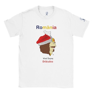 Peut inclure: T-shirt blanc avec un graphisme de Vlad Țepeș, personnage historique, et le mot "România" au-dessus. Le design comprend un chapeau rouge et blanc, et le texte "Vlad Țepeș Drăculea" en dessous.