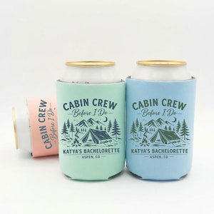 May include: Three can coolers in shades of blue, green, and pink. Each cooler has the text "CABIN CREW - Before I Do-" and "KATYA'S BACHELORETTE - ASPEN, CO" with a camping scene design.