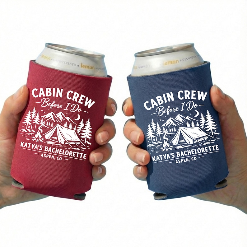 May include: Two can coolers, one burgundy and one navy blue, each with the text "CABIN CREW - Before I Do-" and "KATYA'S BACHELORETTE - ASPEN, CO." The design includes a tent, mountains, trees, and a campfire.