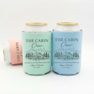 May include: Three can coolers in mint green, light blue, and pink. Each cooler has the text "THE CABIN Crew" and a cabin graphic. The mint and blue coolers also have "DANIELLA'S BACHELORETTE - Aspen, Colorado - Est. 2026".