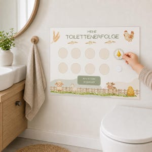May include: A rectangular wall chart titled MEINE TOILETTENERFOLGE featuring illustrations of a chicken, sheep, goat, and cow. The chart includes ten circular spaces for stickers, with one sticker showing a yellow drop placed on the board.