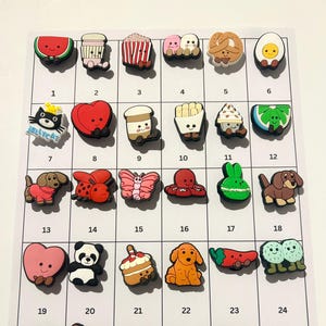 May include: A collection of 30 colorful shoe charms in various shapes and designs. The charms include food items like watermelon, popcorn, and fries, along with animals, hearts, and other cute characters. The "Jellycat" charm is also visible.