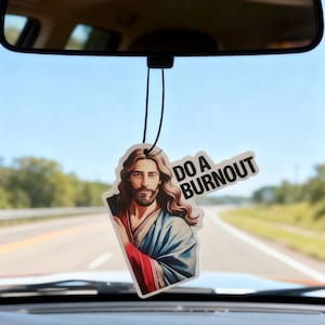May include: An air freshener with an image of Jesus wearing a blue robe and the text "DO A BURNOUT" hanging from a car's rearview mirror. The air freshener is white with a black string.