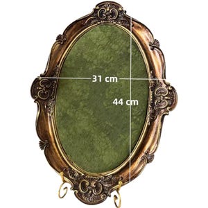 May include: Ornate oval picture frame with a gold and bronze finish. The frame has decorative scrollwork and a green interior. The frame measures 12.2 inches wide by 17.3 inches high.