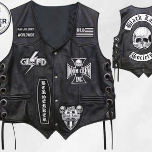 Puede incluir: Un chaleco de cuero negro con múltiples parches bordados que incluyen Black Label Society, Doom Crew Inc y un gráfico de calavera. El chaleco tiene cierre frontal de botones, detalles de cordones laterales con ojales metálicos y un panel trasero con una calavera grande.