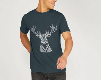 May include: A dark blue short-sleeved t-shirt featuring a white line art graphic of a deer head with large antlers centered on the chest. The shirt has a crew neckline and is paired with dark gray denim jeans.