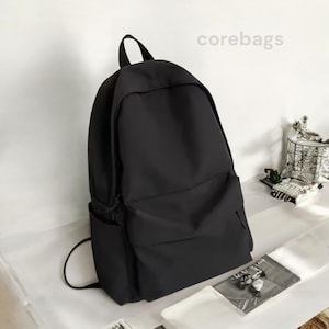 May include: A black backpack with a large main compartment, a front pocket, and side pocket. The backpack has a top handle and adjustable shoulder straps. The text "corebags" is visible in the upper right corner.