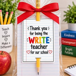 Pode incluir: Um saco de presente de plástico transparente contendo um bloco de notas com papel pautado e um lápis amarelo inserido pela parte superior e inferior. O bloco apresenta o texto: Thank you for being the WRITE teacher for our school, com um laço vermelho.