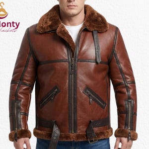 Puede incluir: Chaqueta de cuero marrón con cuello y forro de borrego. La chaqueta tiene cremallera frontal, múltiples bolsillos y detalles de hebilla. La chaqueta tiene un estilo aviador clásico.
