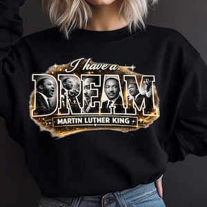 May include: Black sweatshirt featuring a gold-outlined design with the words "I have a DREAM" and images of Martin Luther King Jr. The design includes the text "MARTIN LUTHER KING" in a gold font.