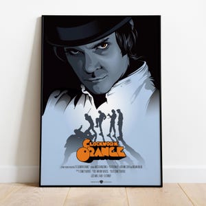 Op de afbeelding: Een ingelijste poster met een gestileerd portret van een man met een bolhoed, met de titel "Clockwork Orange" in oranje en wit. De poster heeft een donkere achtergrond met silhouetten.