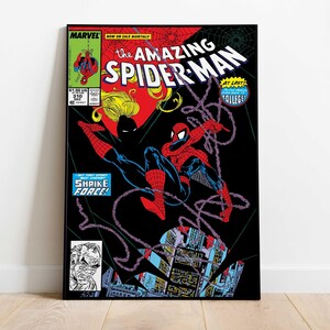 May include: A framed comic book cover of The Amazing Spider-Man. The cover features Spider-Man in a red and blue suit swinging from a web against a black background. The text includes "MARVEL" and "SHRIKE FORCE!"