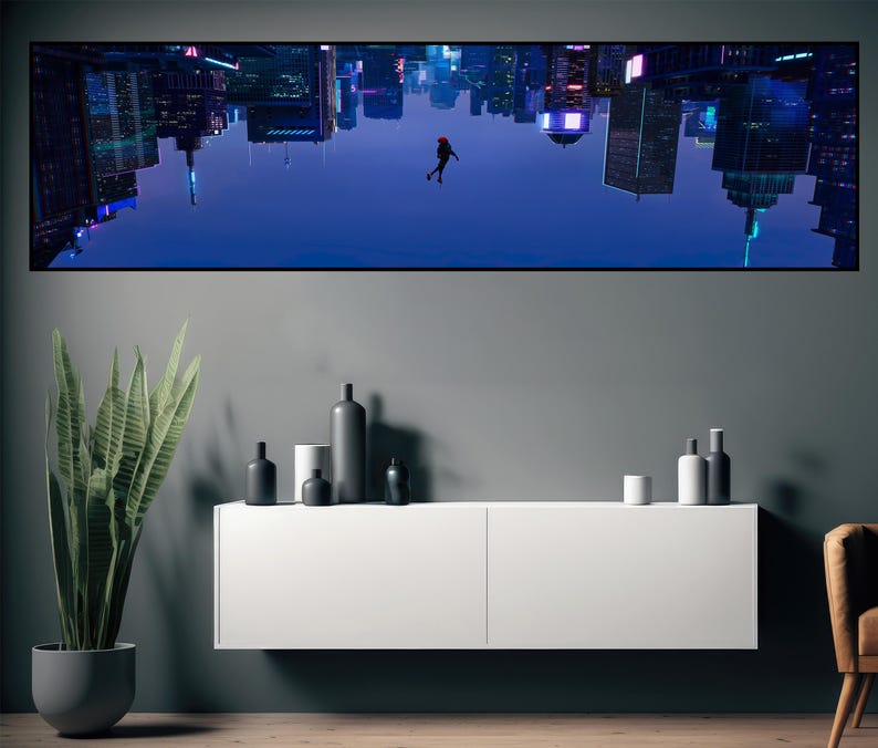 Puede incluir: Una impresi&oacute;n art&iacute;stica enmarcada representa un vibrante paisaje urbano invertido con una figura en el aire. La obra de arte est&aacute; montada sobre un mueble blanco, complementada con botellas negras decorativas y una planta en maceta. La paleta de colores incluye azules, negros y blancos.