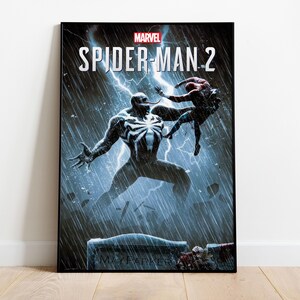 May include: A framed poster featuring the Marvel logo and the title "SPIDER-MAN 2." The artwork depicts a battle between Spider-Man and Venom in a stormy, rain-filled environment with lightning strikes. The poster has a black frame.