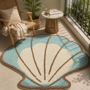 May include: A seashell-shaped rug with a light blue, cream, and brown color scheme. The rug is placed on a tiled floor, with a wooden chair, side table, and potted plants in the background. The rug's design features a detailed shell pattern.