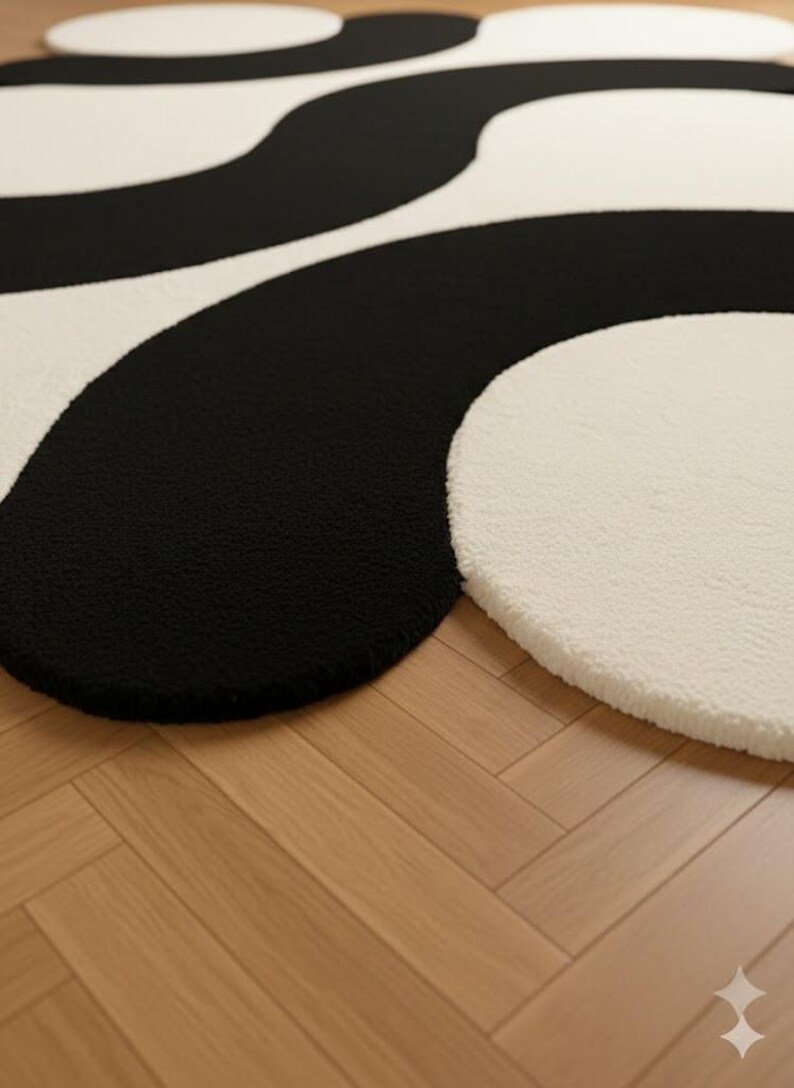 May include: A modern, abstract rug featuring a bold black and off-white design. The rug has a soft, textured surface and a unique, flowing pattern. The contrasting colors and organic shapes create a stylish accent for any room.