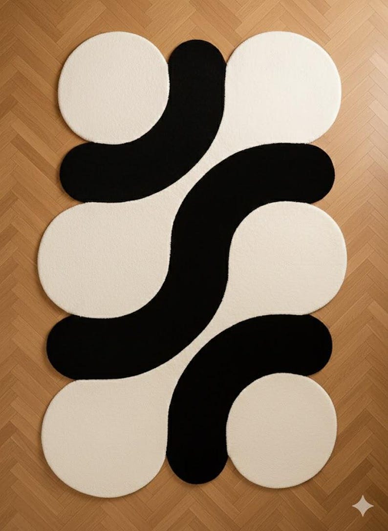 May include: A modern area rug with a bold, abstract design. The rug features a pattern of interconnected shapes in black and off-white. The design includes large, rounded forms that create a striking visual contrast, suitable for contemporary interiors.