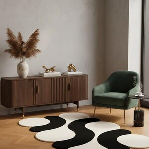 May include: A modern living room scene featuring a black and white abstract rug. The rug's design is composed of interconnected circular shapes. A dark wood cabinet, green armchair, and decorative items complete the stylish interior.