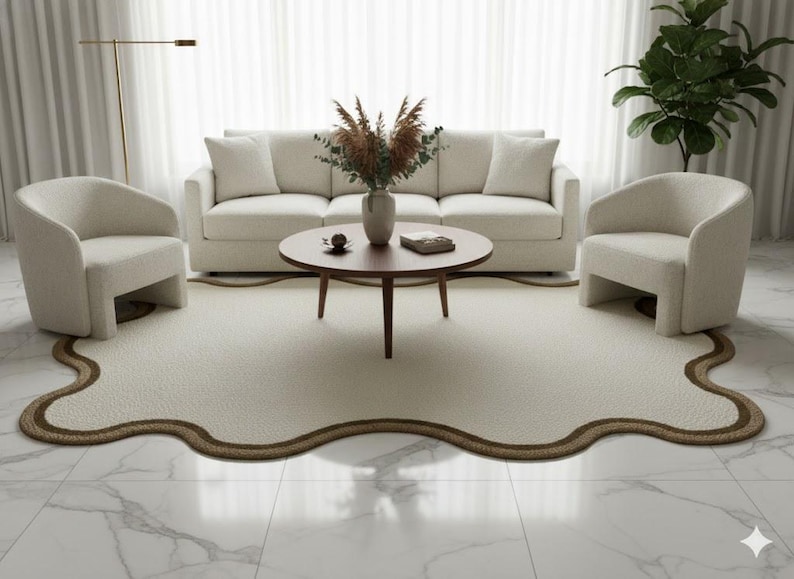 May include: A modern living room setup featuring a cream-colored sofa, two matching armchairs, and a round wooden coffee table. A unique, cream-colored rug with a brown border sits on a marble floor, creating a cozy and stylish space.