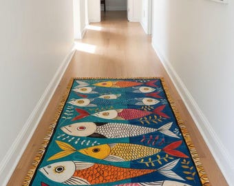 May include: A rectangular, blue rug with a repeating pattern of colorful fish. The fish are in shades of yellow, orange, pink, and white, with red and yellow fins. The rug has a fringed border and is placed on a wooden floor.