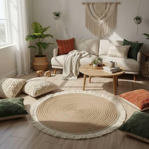 May include: A living room with a beige sofa, a round wooden coffee table, and a natural fibre rug. Decorative cushions in green, beige, and rust are scattered around. A large potted plant and macrame wall hanging create a bohemian style.