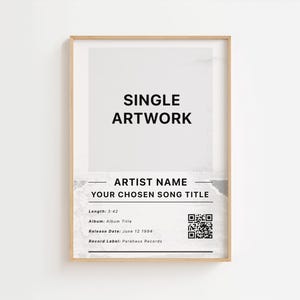 May include: A framed print with a minimalist design. The artwork features the text "SINGLE ARTWORK" in bold black letters. Below, it includes space for artist and song details, along with a QR code and release information. The frame is a light wood colour.