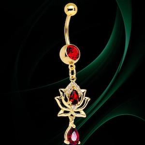May include: Gold-colored belly button ring with a curved barbell design. The ring features a large, round, red gemstone at the top and a smaller red gemstone at the bottom. A gold lotus flower with a red gemstone and small clear stones hangs from the center.