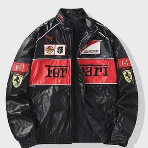 Puede incluir: Chaqueta de carreras Ferrari negra y roja con detalles blancos. Presenta el logotipo de Ferrari, logotipos de patrocinadores y la palabra "Ferrari" en el pecho. Cuello alzado y cierre de cremallera.