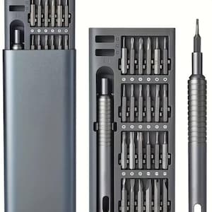 May include: A dark gray precision screwdriver set featuring a rectangular storage case with a sliding tray. The set includes a cylindrical handle and a variety of interchangeable metal bits organized in labeled slots within the internal tray.